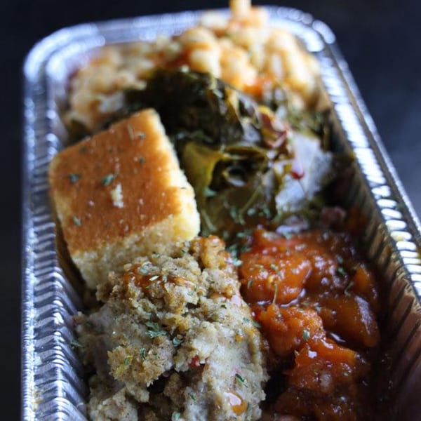 A Jive Turkey soul food meal in a foil container with cornbread, collard greens, mac and cheese, and candied yams.