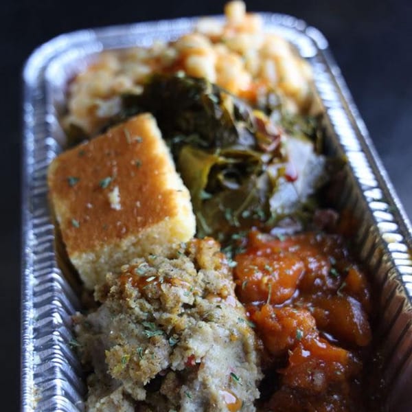 A Jive Turkey soul food meal in a foil container with cornbread, stuffing, collard greens, and mac and cheese.