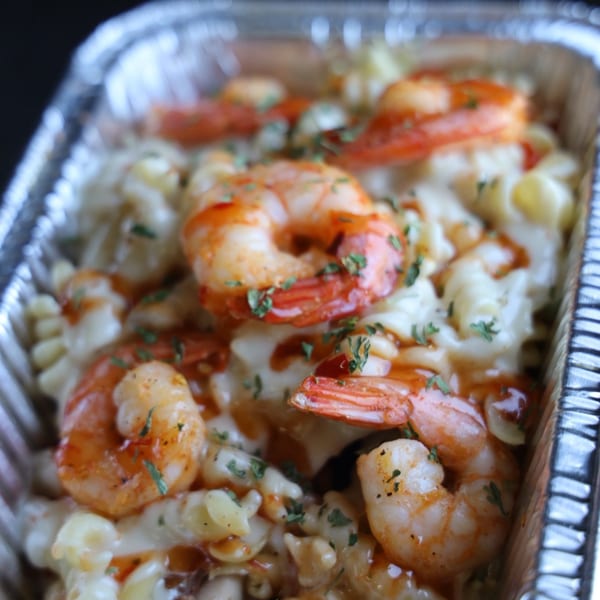 Shrimp mac and cheese with sauce and parsley in a foil container from Jive Turkey.